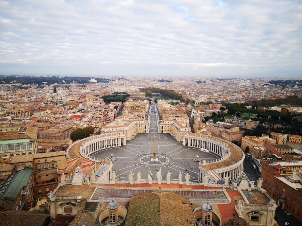 View of St Peters Square from the roof of the church: a round plaza with a curve of columned colonnades on either side.