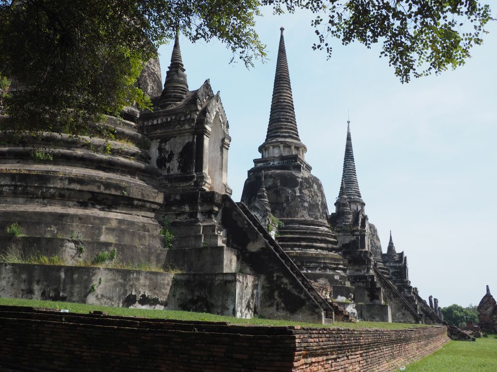 Three large bell-shaped stupas, all intact, with stairways leading up into them.