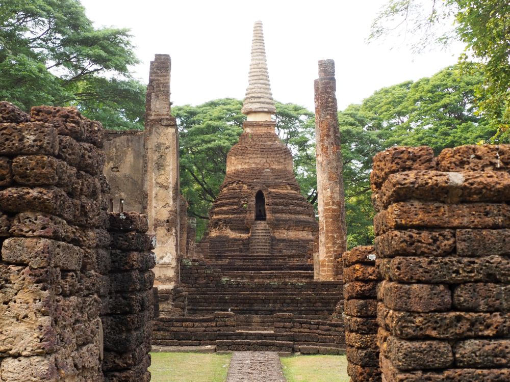 Two square columns of laterite blocks form an entryway to what used to be an assembly hall with, at its end, a simple bell-shaped stupa that tapers to a point.