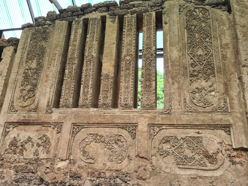 The wall has horizontal rectangular panels below and narrow vertical panels above that would let air and light through but still keep the inside shaded. The panels have flowery raised decorations.