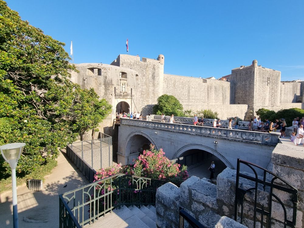 A view of a bridge with rounded arches leading to the city wall, with an arched gateway.