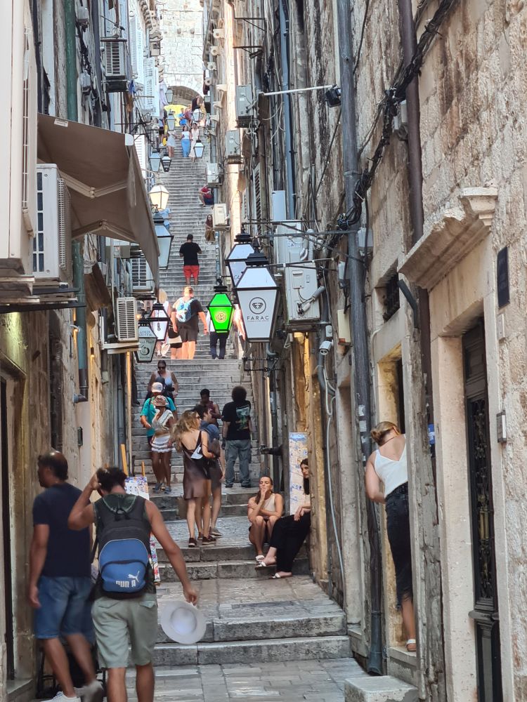 A narrow side street, high buildings on each side. It becomes stairs after about a block.