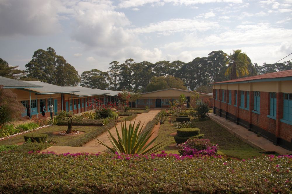 Single-story buildings arranged in a rectangle, with neat plantings in the space in the middle.