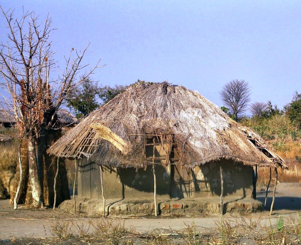 A mud house with a thatched roof in poor condition.