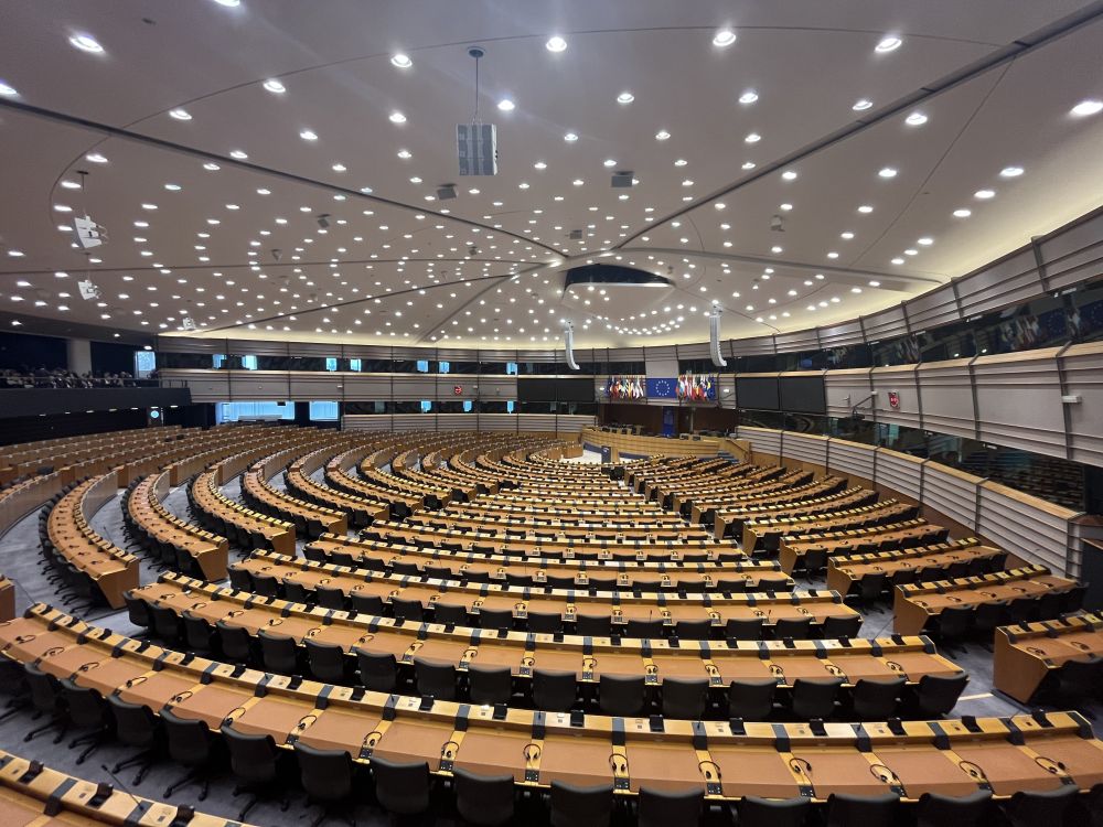 A very large hall with tables and chairs in concentric rows forming almost a half circle.