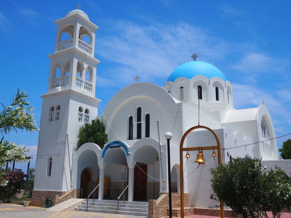 A pretty white church with a tall bell tower and a bright blue dome.