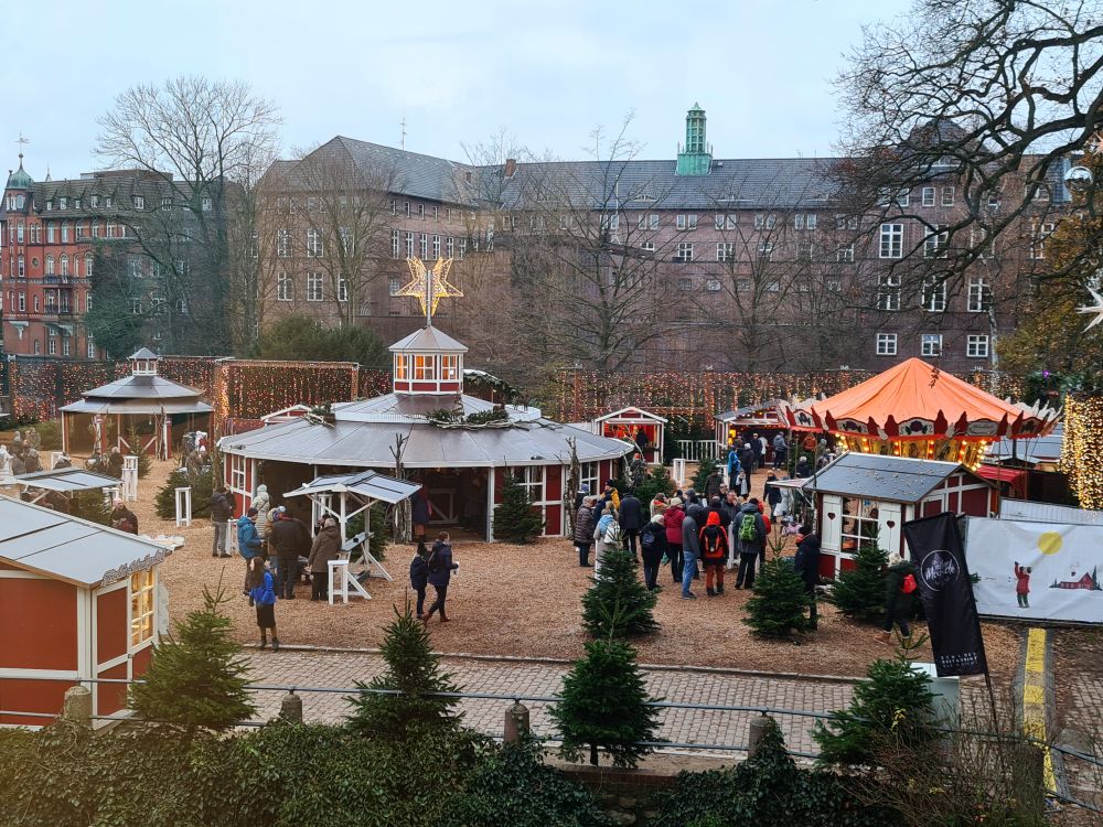 Widely-spaced structures: a round one in the middle, a carousel on the right, and a few stalls dotted around a flat open space.