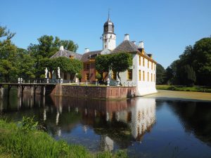 View of the building from across the moat opposite one of its corners. Both wings are somewhat visible here, though the front is mostly obscured by trees.