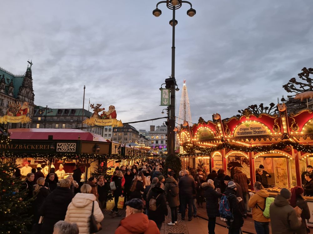 In a darkening late afternoon, crowds of people in between two rows of market stalls.