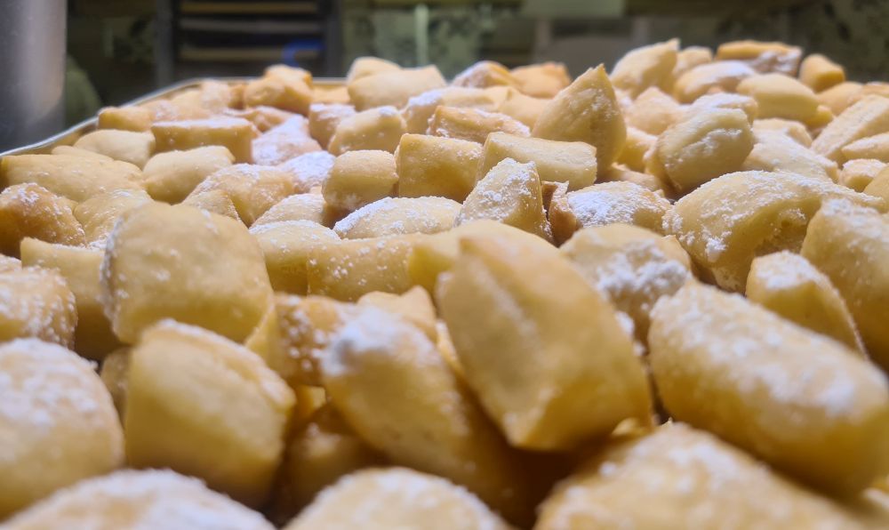 A pile of small white baked goods, powdered with sugar.