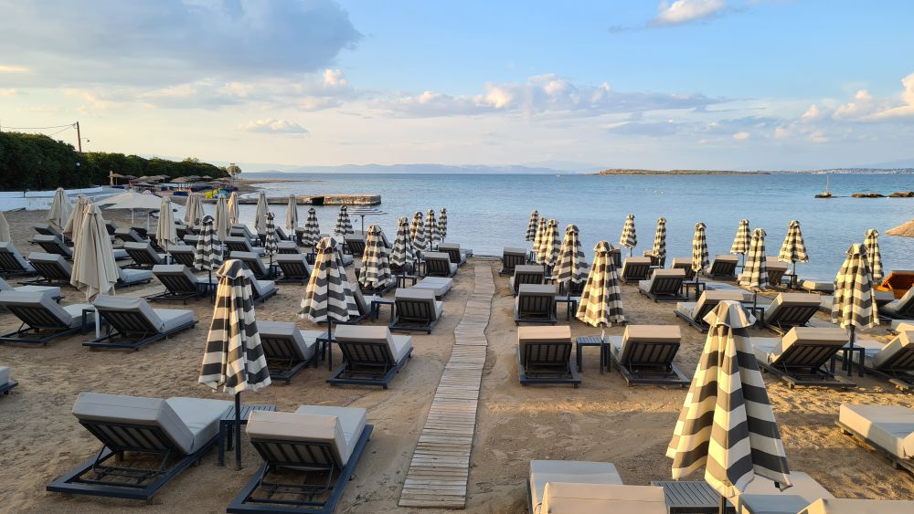 Looking toward the water, the beach is covered with neat lines of beach loungers and closed umbrellas.