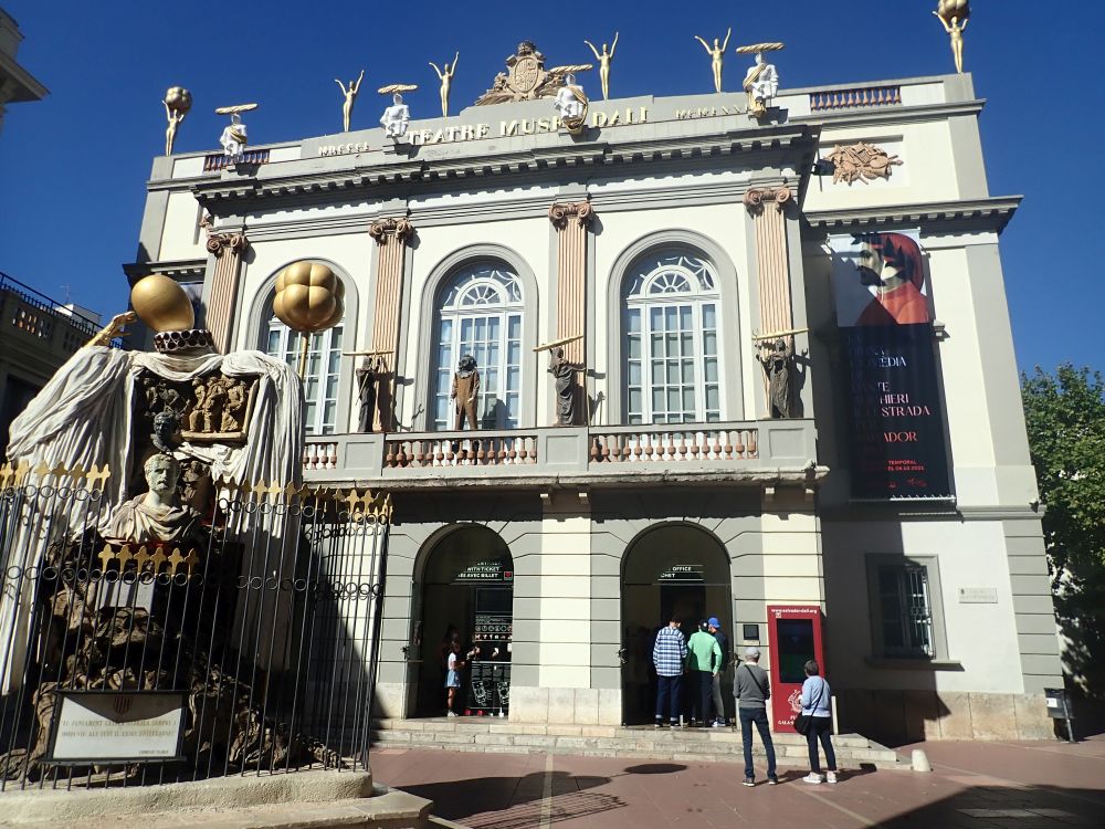 A two-storey neo-classical expterior, but with odd statues above the arched entranceways.