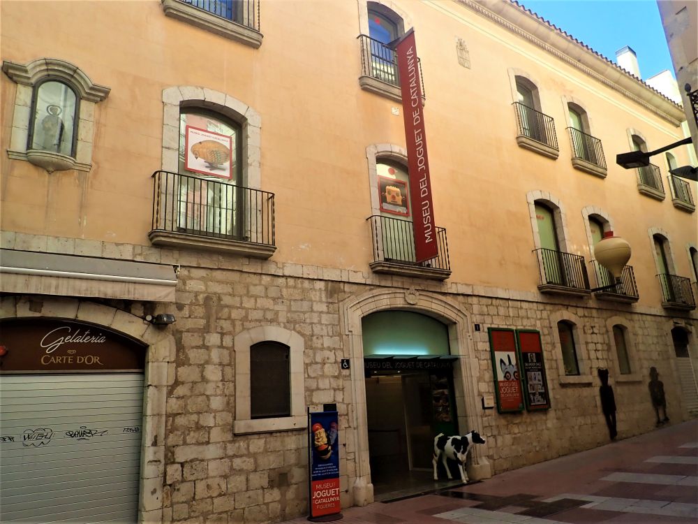 The building is rather plain: stone brick sided on the ground floor and stuccoed on the two floors above that. A not-very-prominent sign says it is the toy museum, and a statue of a calf stands in the doorway.