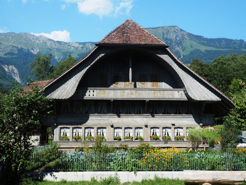 A very pretty chalet with an interesting framed balcony. Mountains in the background.