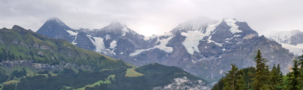 Three mountain peaks in the distance, snow-topped but also with clouds obscuring their very tips.