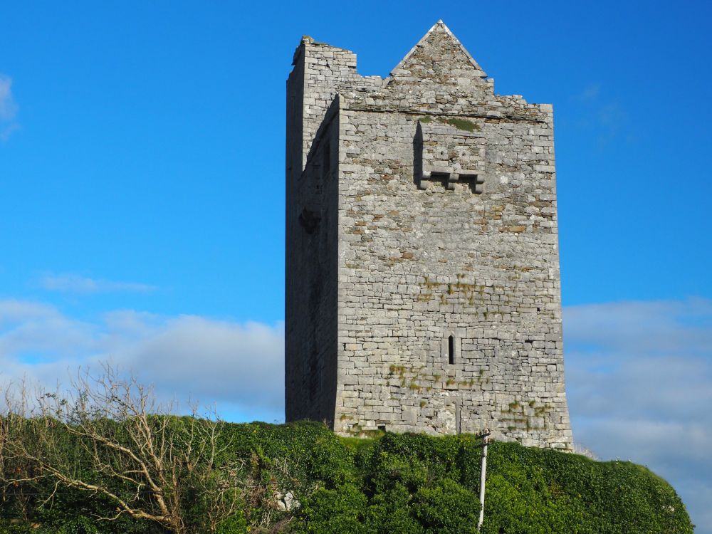 A tall, square stone castle on a hill.