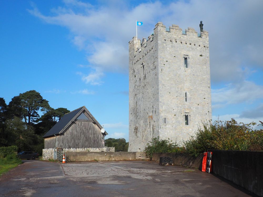 A square and tall stone castle, with a very large human-shaped statue on the roof.