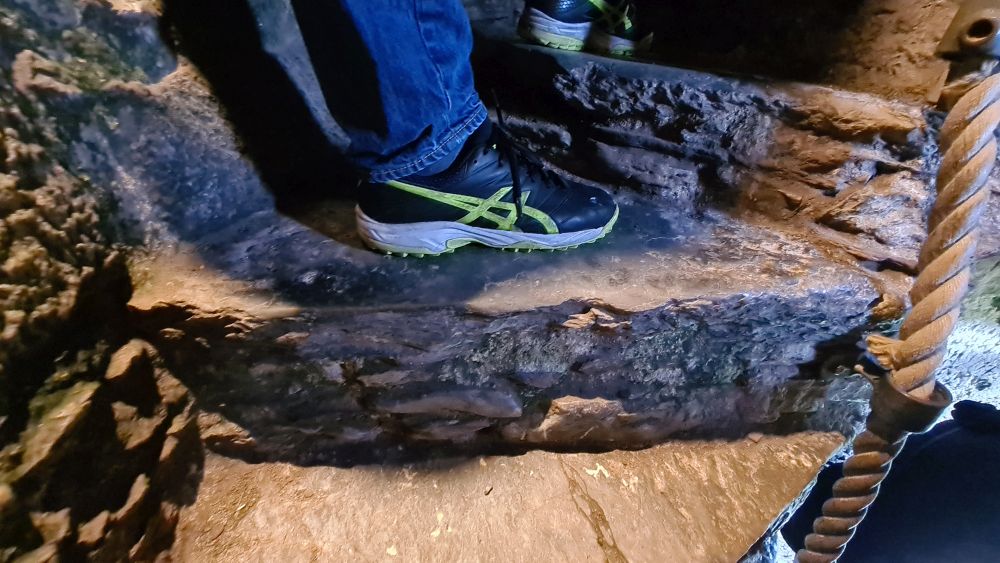 Two stone steps, with a person standing on both, a foot on each.