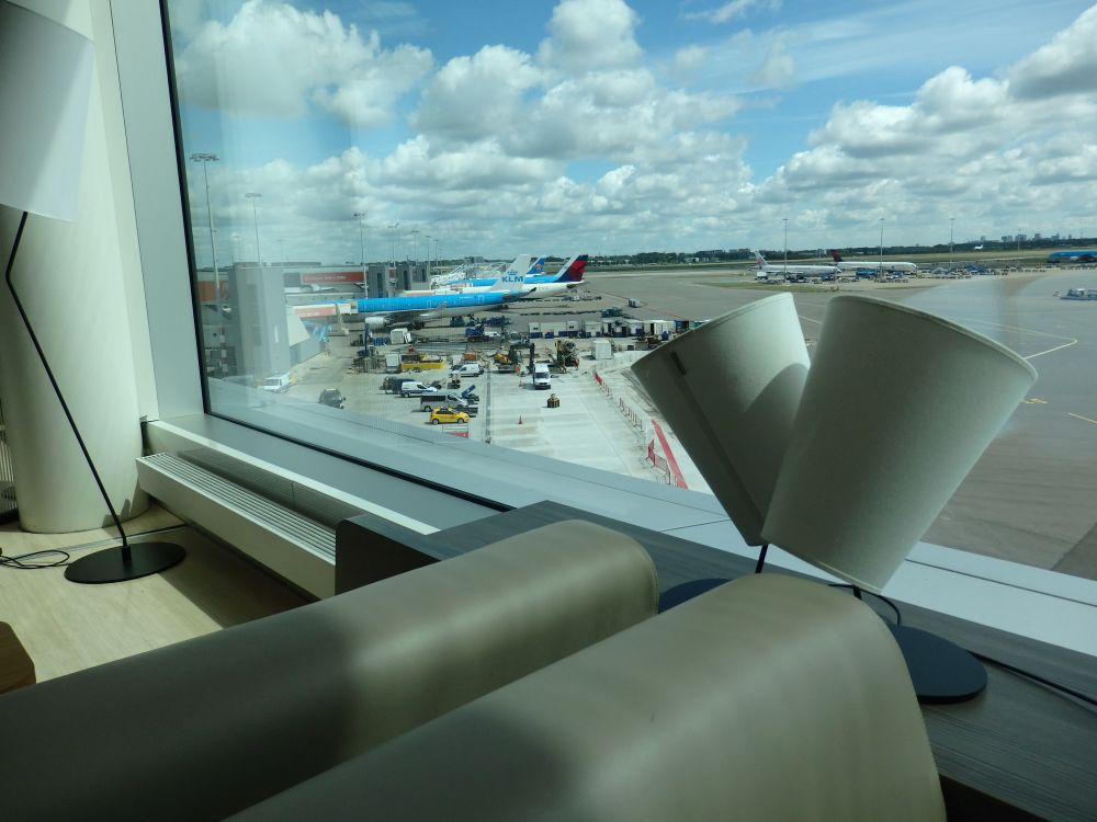 backs of two leather counches and beyond them, a view of some gates with planes parked at them.