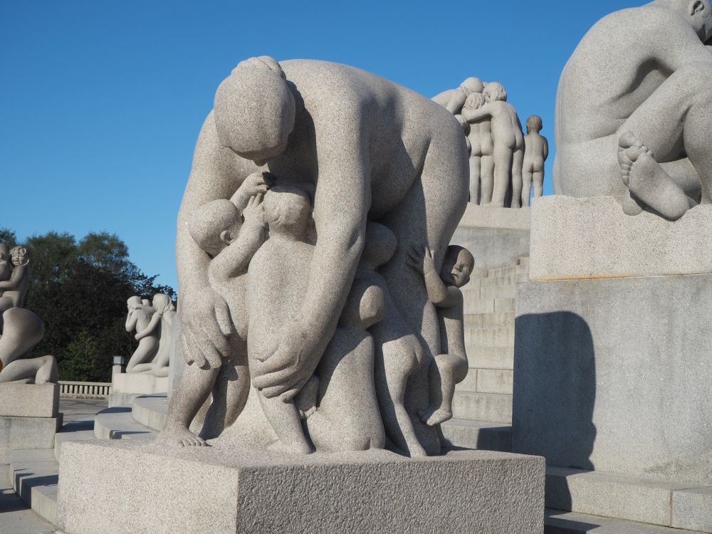 In the statue, a heavy and naked woman bends down at the waist, with many children under her reaching up to her. It's as if she's trying to hug them all at the same time.