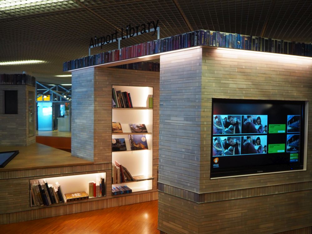 A square of bookshelves with a doorway in, where a few books are visible on the shelves.