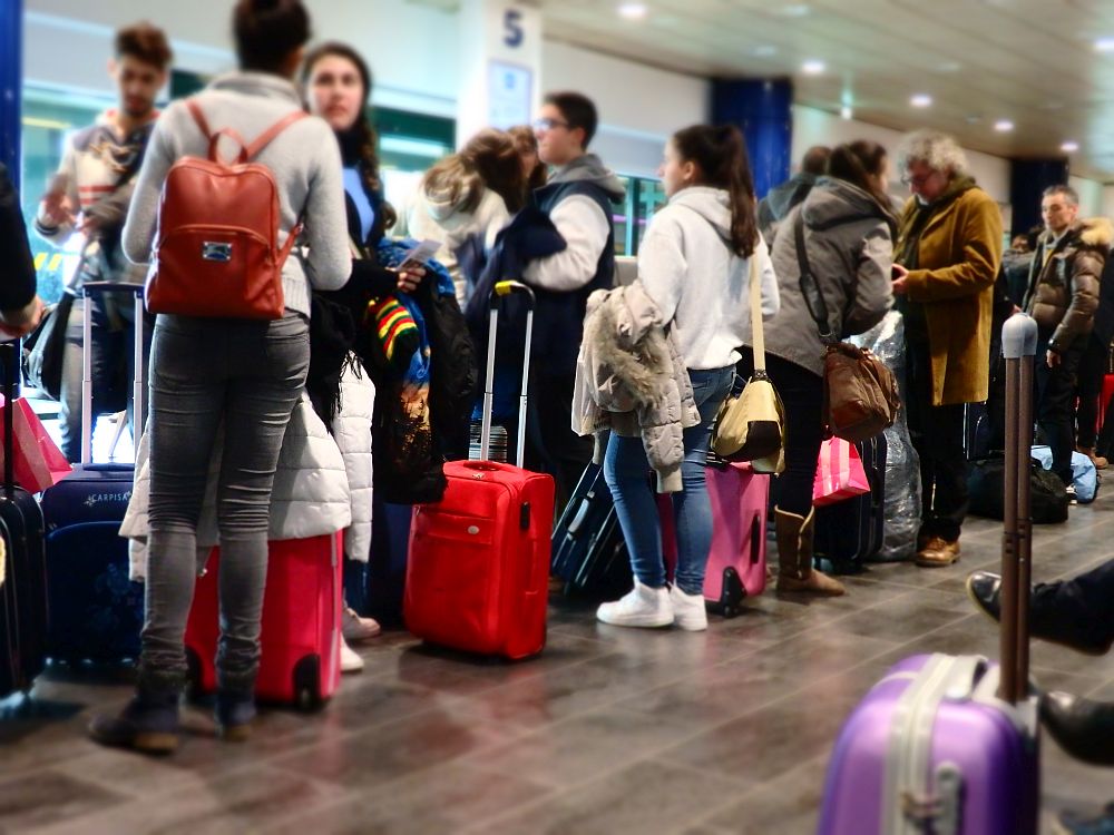 People waiting in line with wheeled carry-on bags.