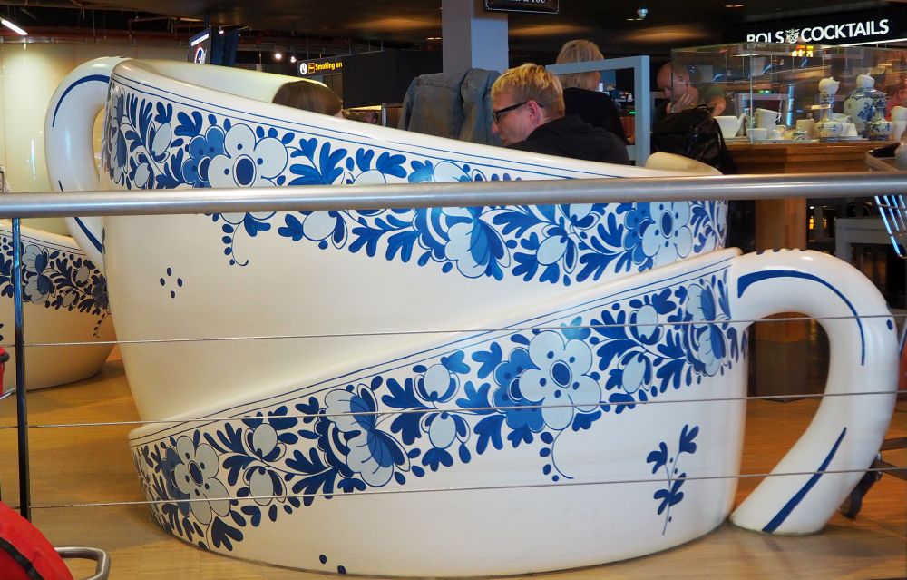 What looks like 2 teacups with Delft blue patterns one on top of the other, but two people are sitting inside.