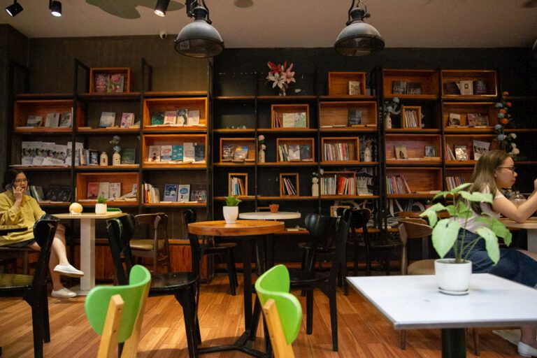 A coffee shop. Small tables, bookshelves along the wall.