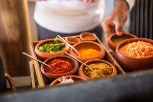 A tray of small clay pots, each with a different powder or chopped veg.