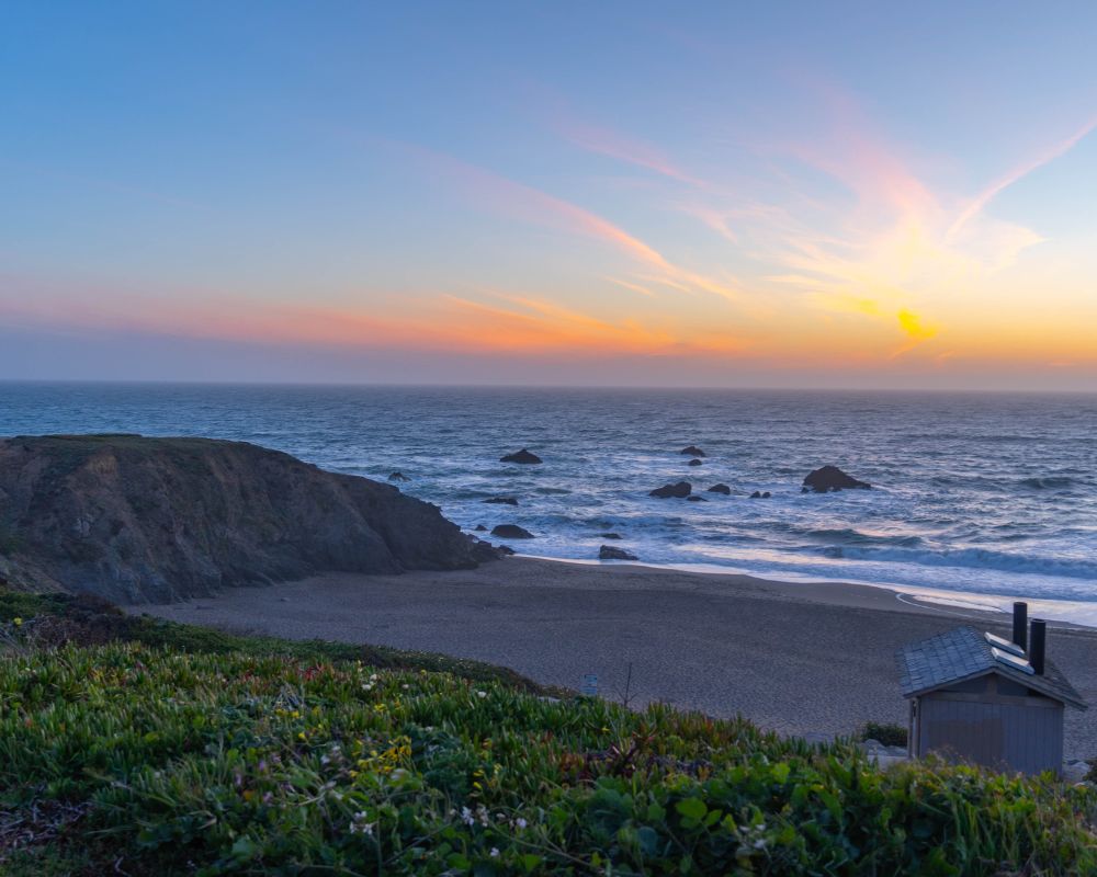 A view over a beach at the sunset over the sea.