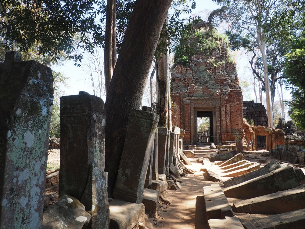 A tall temple with a door in its center, and a row of monoliths standing along the way to it, while another row has fallen opposite them.