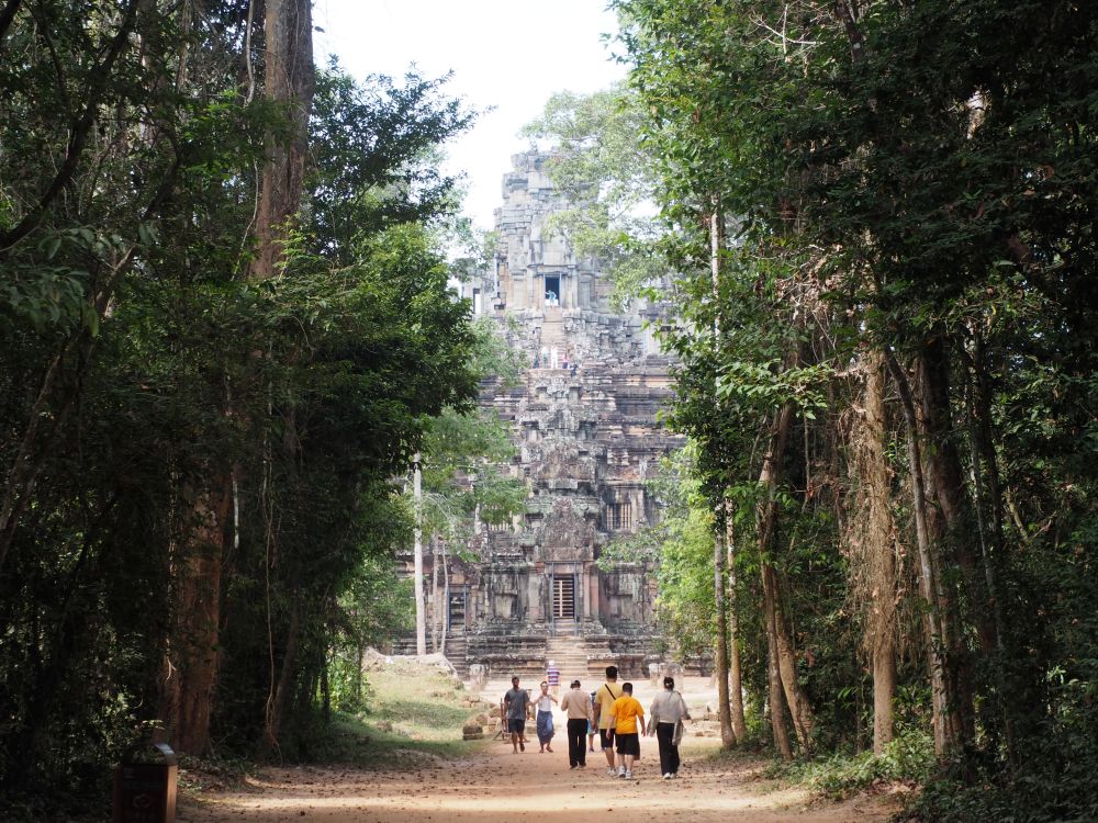 A large pyramid temple, seen from down a tree-lined walkway.