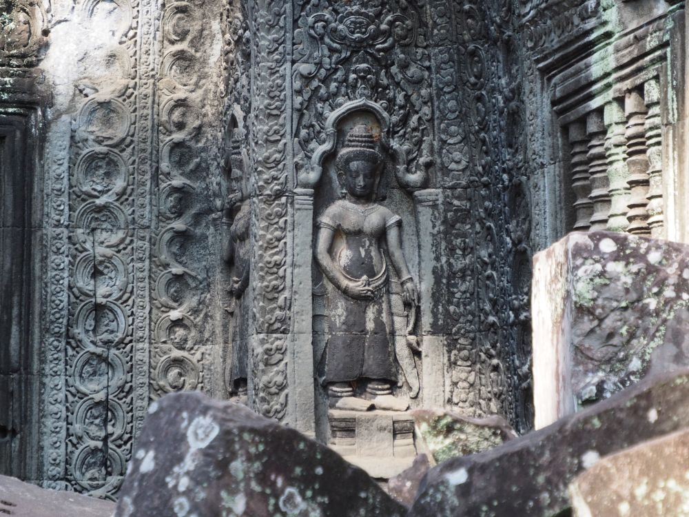 A figure of a female god carved into a stone surface, with decorative motifs around her.