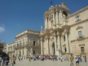 A grand cathedral in white with many pillars around and above the entrance.