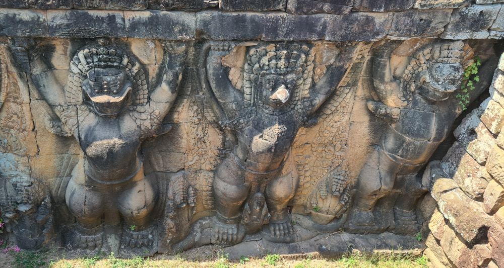 Bird-like creatures carved in stone with their arms raised.