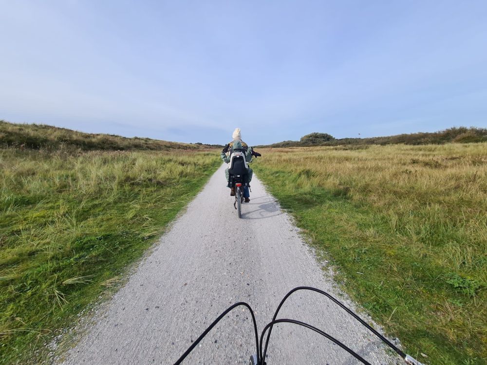 A gravel bike path straight ahead, with a single bicyclist ahead on the path. 