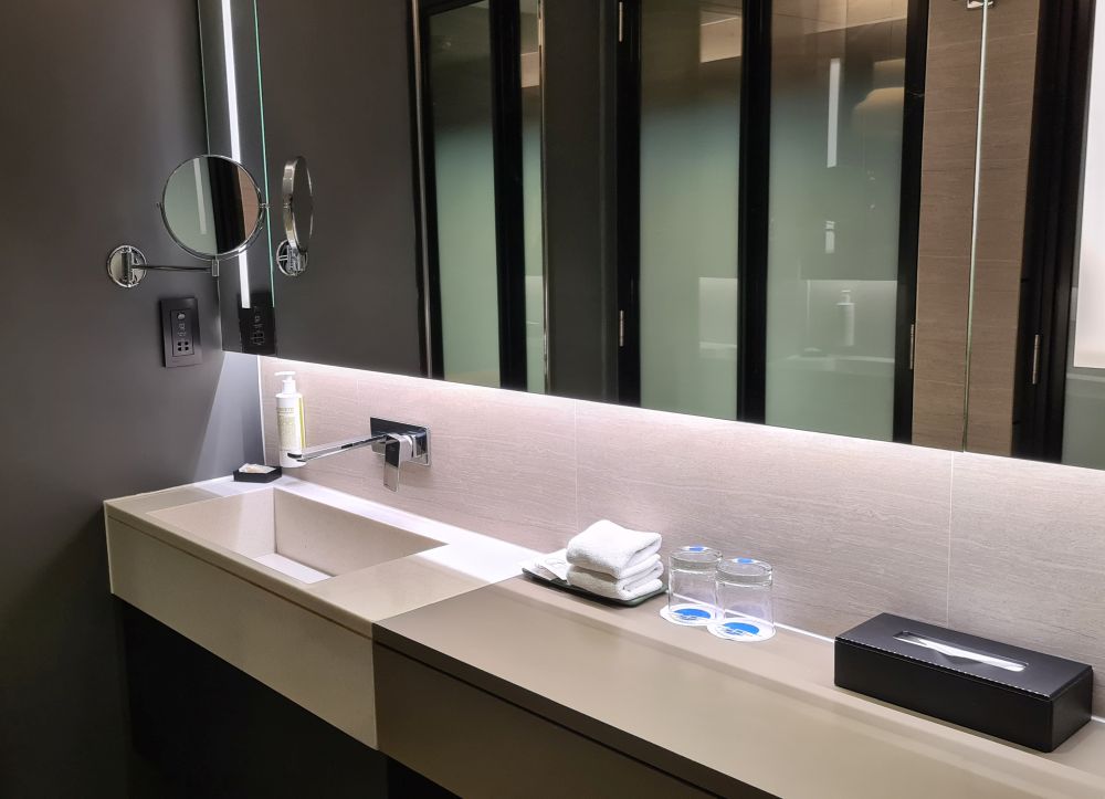 A long counter with a sink at one end, mirror above showing glazed glass doors.