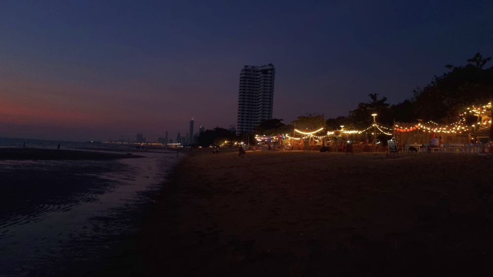 A dark beach, but with a line of businesses lit by strings of lights.