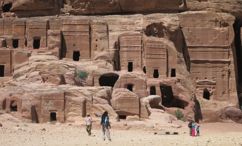 Tombs cut into a cliff wall, with doorways and some decorative carvings.