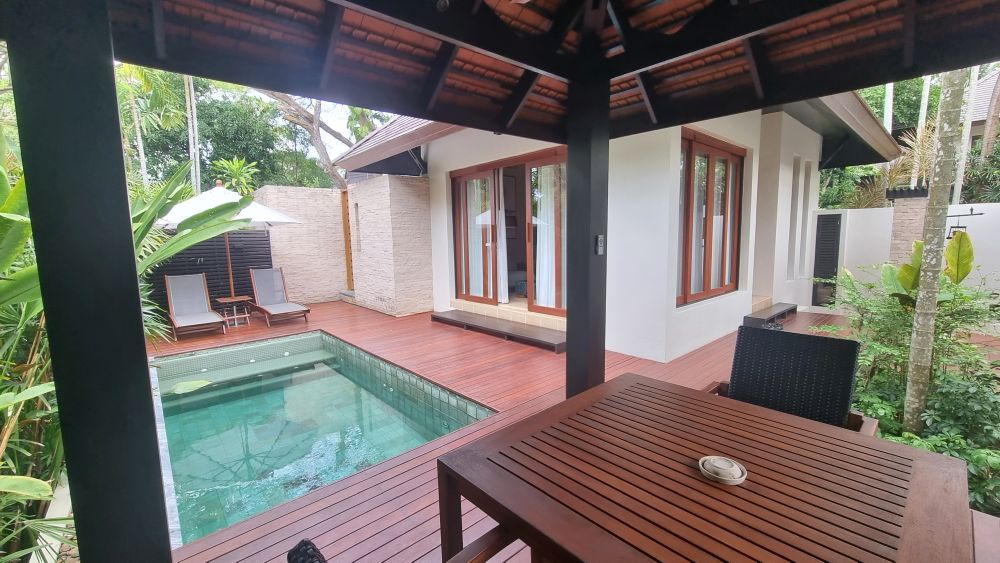 From under an open-sided roof, the whitewashed villa is visible as well as the pool.