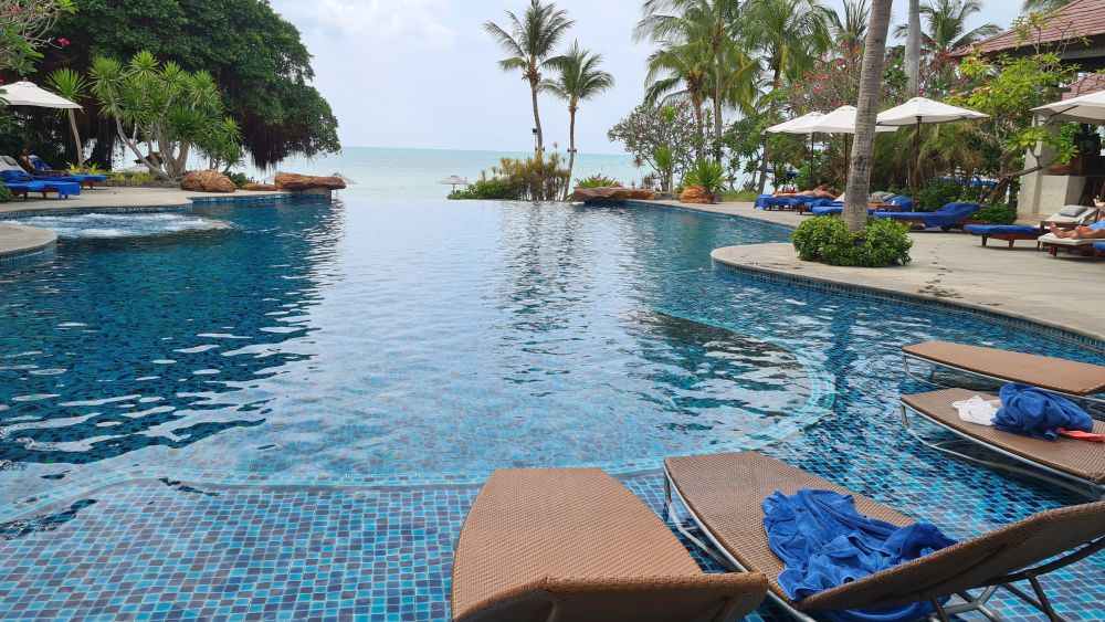 A pool with lounge chairs and palm trees at Sea Sand Sun Resort & Spa.