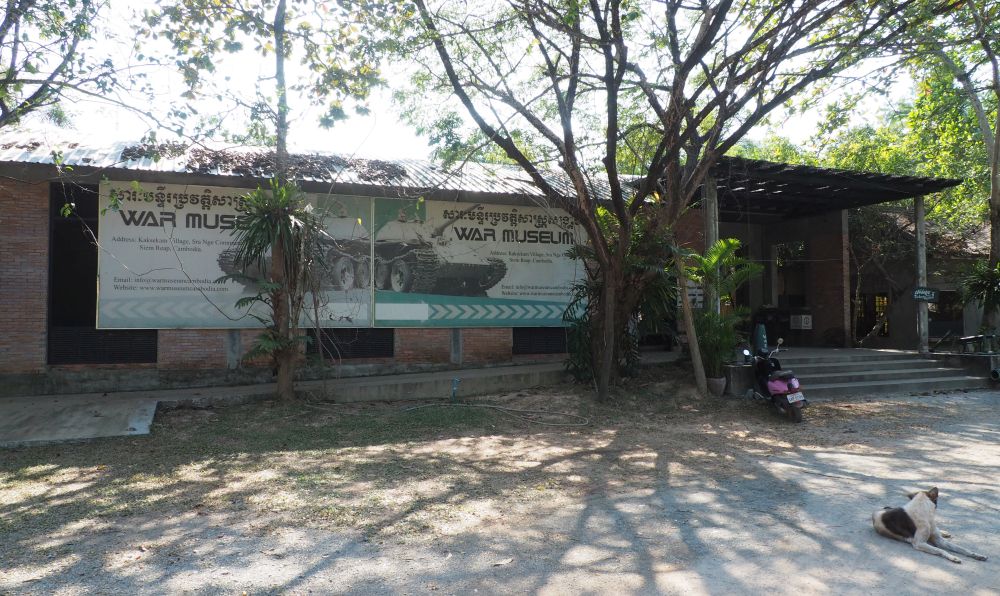 The single-story building at the Cambodian War Museum with trees around it.