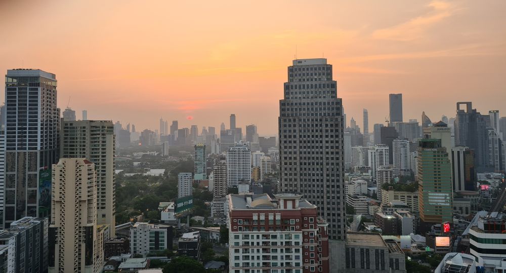 City buildings - lots of skyscrapers - with the sun setting in the background.