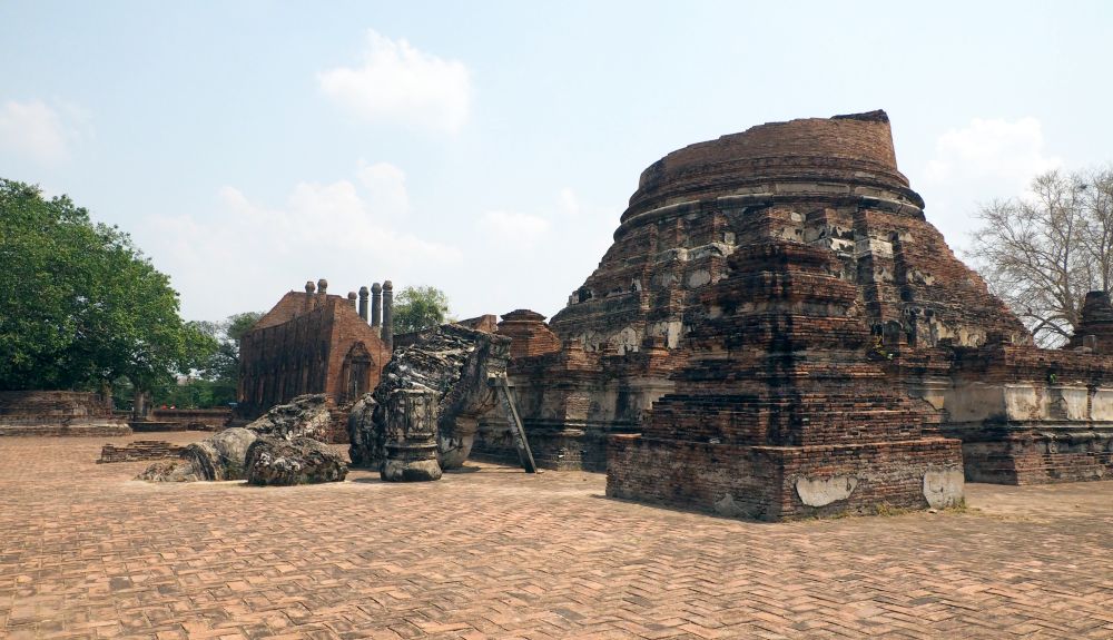 The base of the stupa is round on a square platform and the top is lying on its side next to the platform.