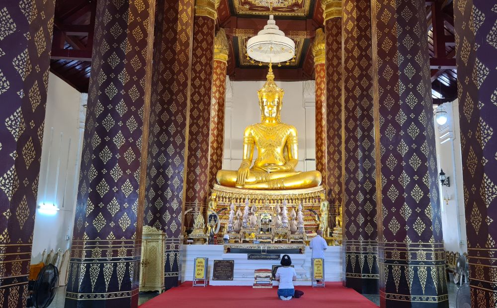 Inside Na Phra Men Temple, with red pillars on both sides and a golden sitting buddha statue at the far end. 