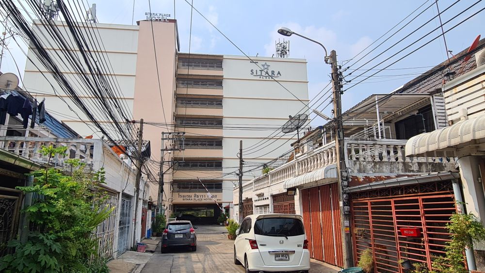 Sitara Place as seen looking down a street lined with 2-storey residences. The hotel towers above them at about 8 storeys.