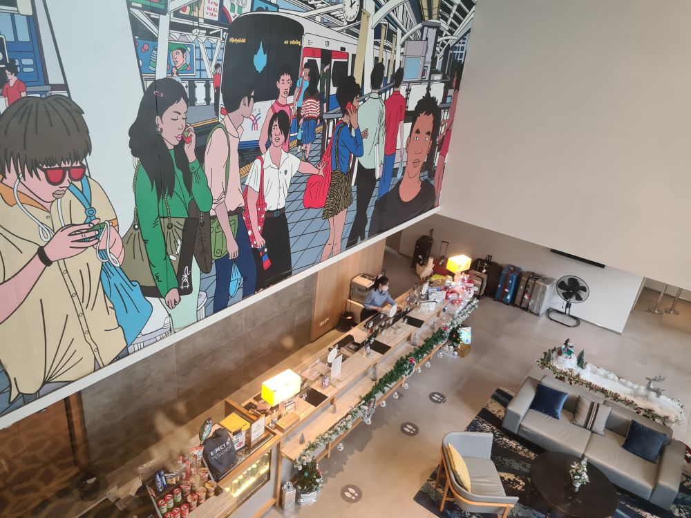 Looking down on a large lobby with a reception desk along one side, a very large mural covering the wall above it.