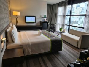 Large hotel room with a big bed facing a wall that is entirely a window.