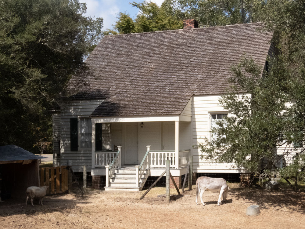 A wooden house, painted white, with a small porch and shingle roof.