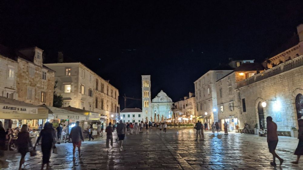 A plaza at night, with the old stone buildings around it lit up.